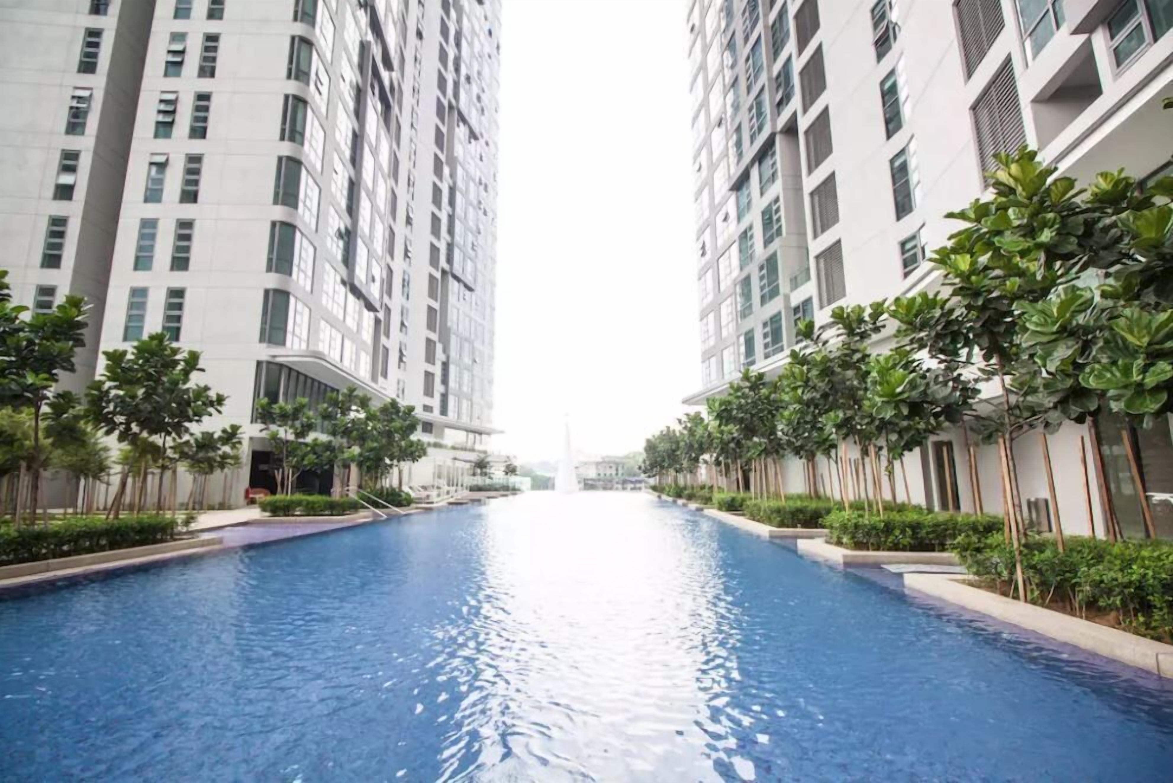A swimming pool flanked by high-rise residential buildings with a clear view of the sky.