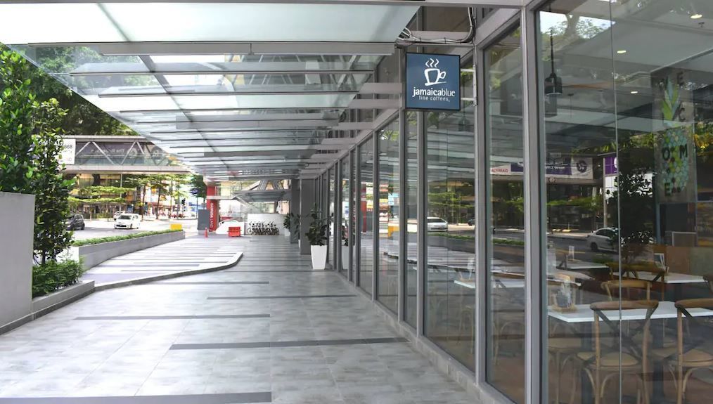 A modern cafe with a glass facade, outdoor seating, and a clear view of the street.