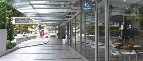 A modern cafe with a glass facade, outdoor seating, and a clear view of the street.