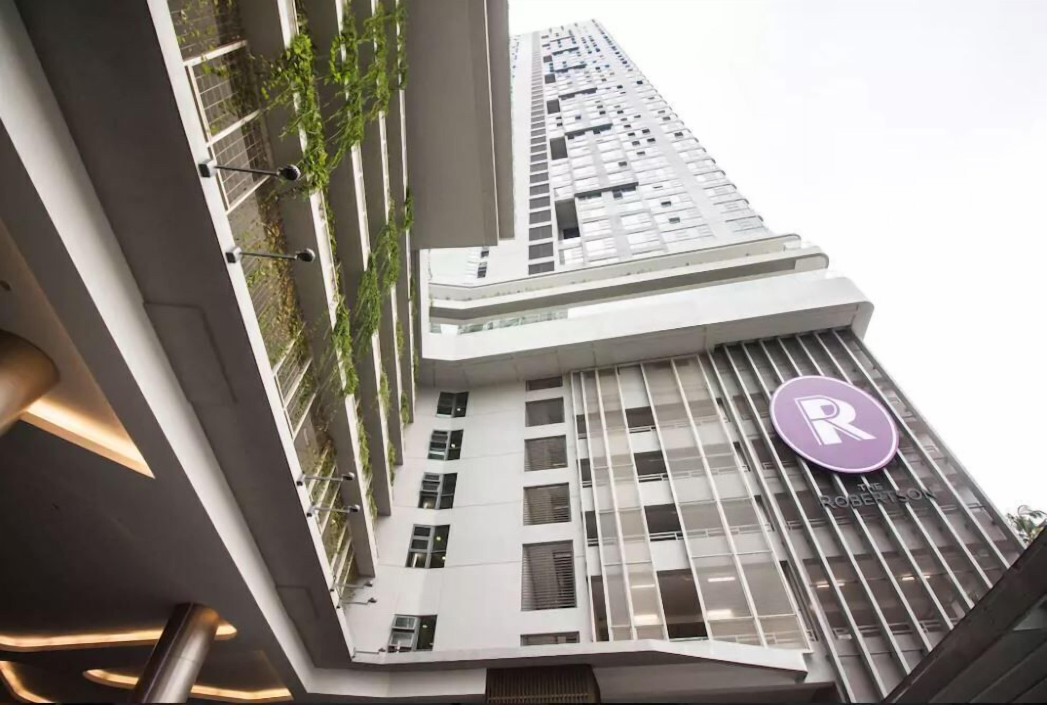 Un moderno edificio de gran altura con un llamativo logo en forma de 'R' en la fachada, que indica que se trata de un hotel.