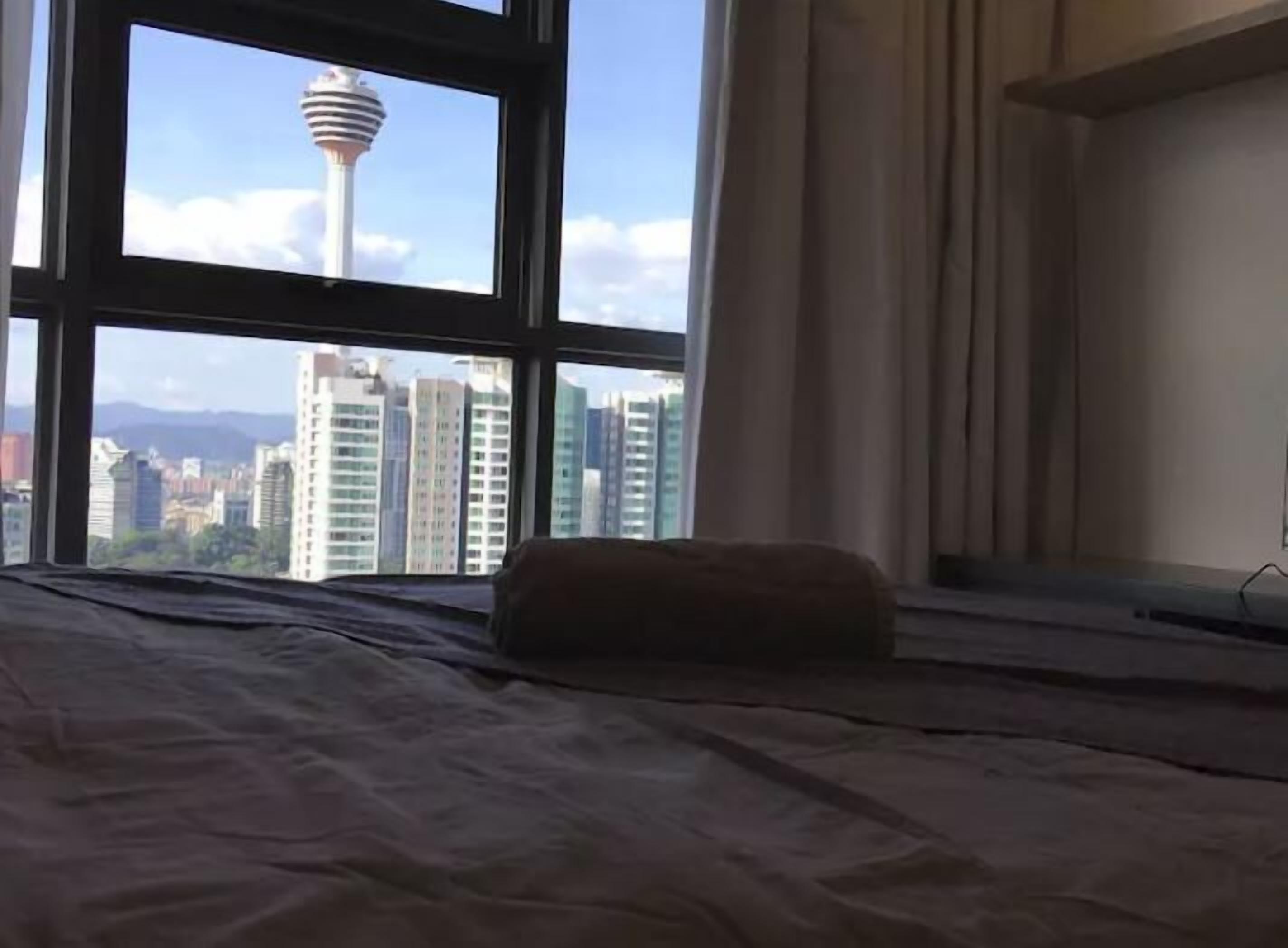 A hotel room with a large window offering a view of a cityscape and a distinctive tower.