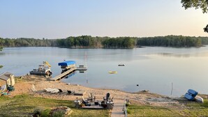 A lakeside property with a dock, lounge chairs, and a paved walkway.