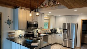 A modern kitchen with a large island, stainless steel appliances, and wooden ceiling beams.