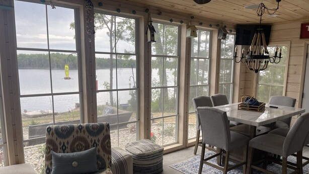 A sunroom with large windows, a dining table, and a patterned armchair.
