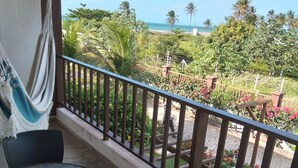 Un balcone con vista sull'oceano, un'amaca e un tavolo con sedie.