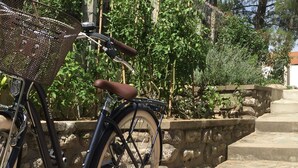 Una bicicleta estacionada sobre escalones de piedra con una cesta y asiento marrón.