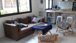 Una sala de estar moderna con un sofá marrón, una mesa azul y sillas de mimbre.