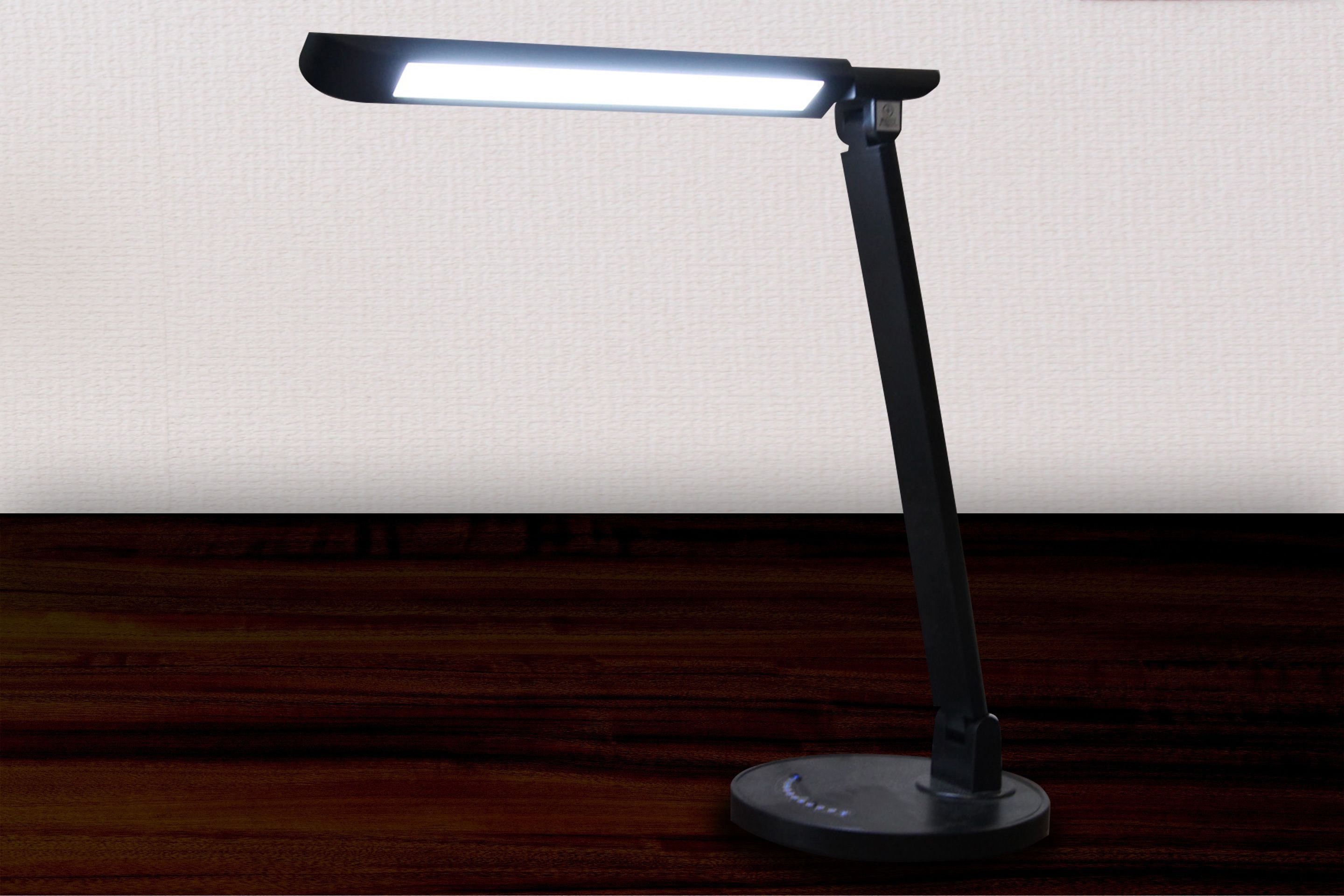 Une lampe de bureau avec une source de lumière rectangulaire, posée sur une surface en bois foncé.