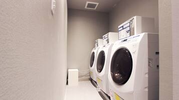 A laundry room with three stacked front-loading washing machines.