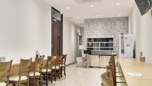 A conference room with a long table and chairs, a kitchen area with a refrigerator and shelves, and a patterned wall. - Hotel Trend Okazaki-Eki Mae (Okazaki)