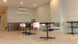 Un hall de hotel con una mesa de recepción, varias sillas, mesas y un reloj en la pared.