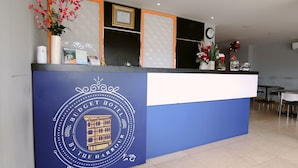 Un mostrador de recepción con una decoración azul y blanca, un certificado enmarcado y un florero con flores.