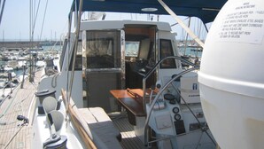Cubierta de barco con timón, panel de control y puerta de camarote.