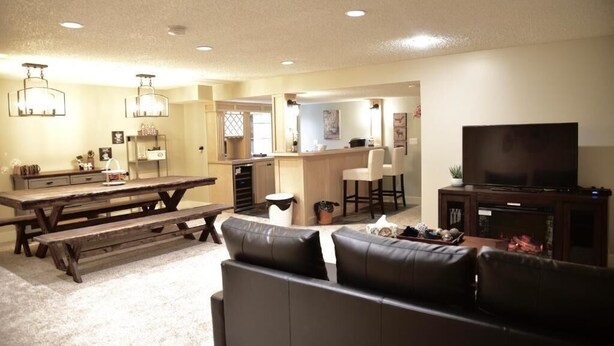 A living room with a dark leather sofa, a wooden dining table, and a TV. - Calgary Cozy Home (Calgary)