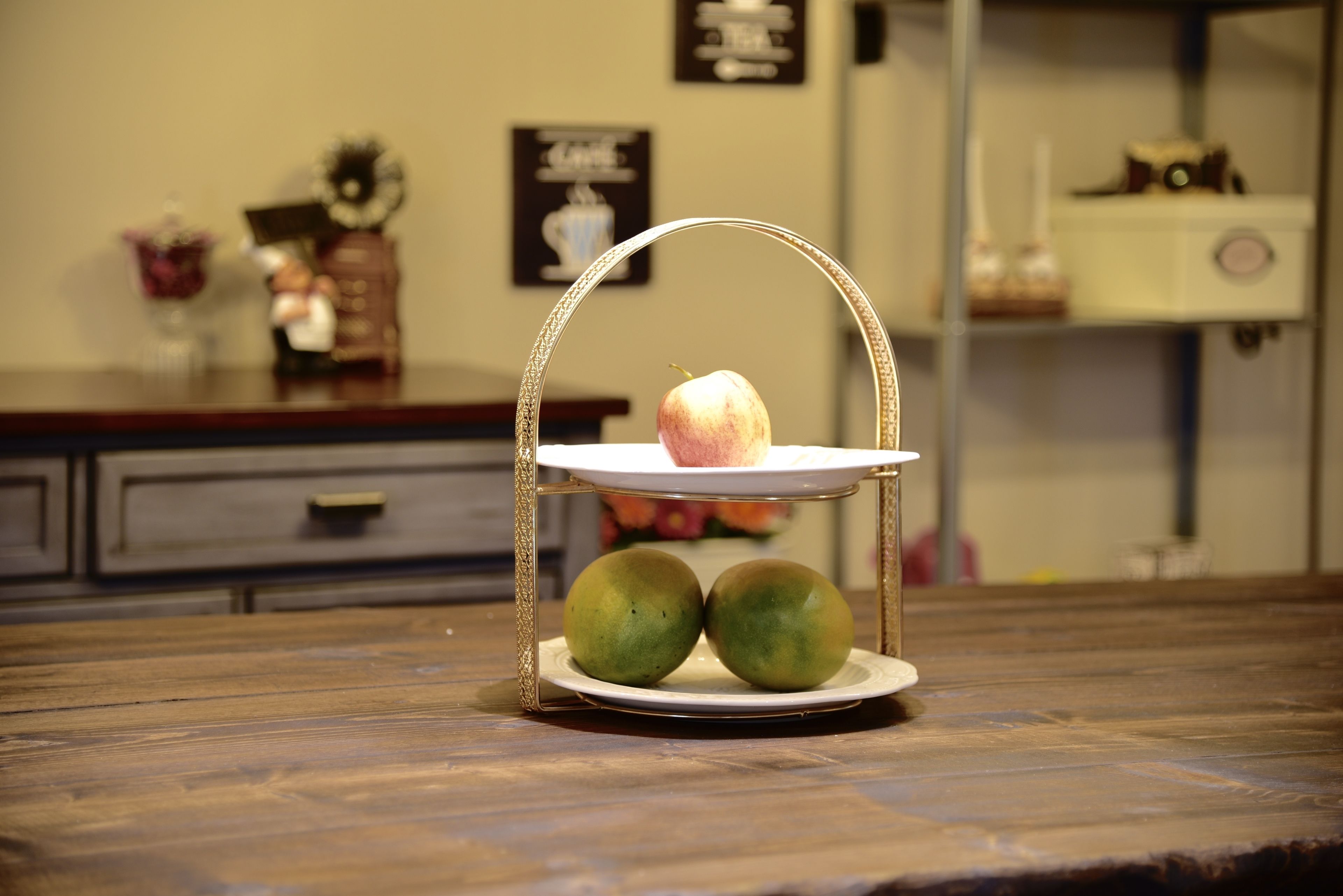 A fruit stand with a pear and two green apples on a wooden table.