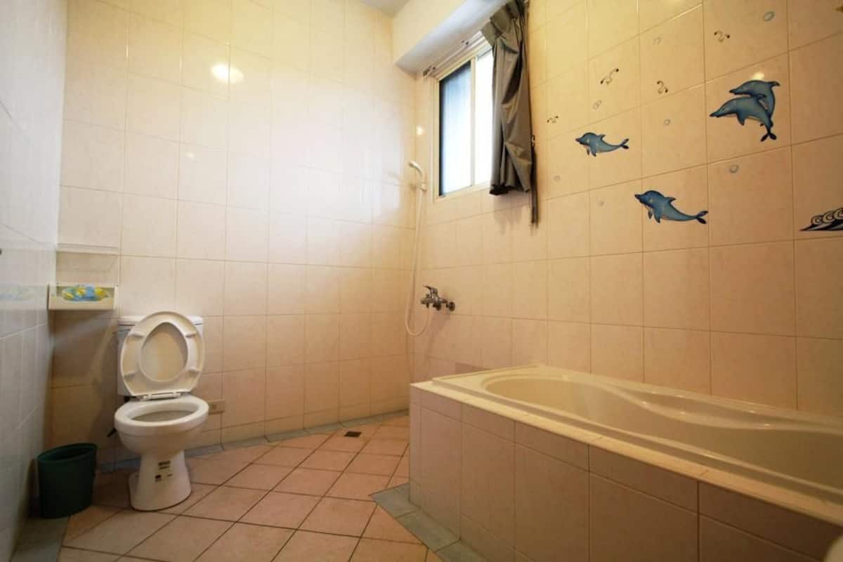 A bathroom with a toilet, bathtub, and dolphin wall decals.