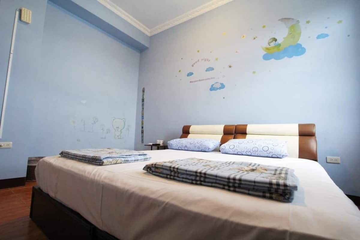 A bedroom with a bed, pillows, and a wall with a night sky mural.