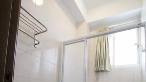 A bathroom with a toilet, a shower enclosure, and a window with curtains. - Equuleus Homestay (Magong)
