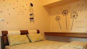 A bedroom with a bed, pillows, a wall with a dandelion decoration, and a wall clock. - Equuleus Homestay (Magong)