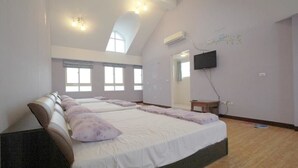 Un dormitorio amplio con dos camas, ventanas grandes, un televisor de pantalla plana y un tragaluz.