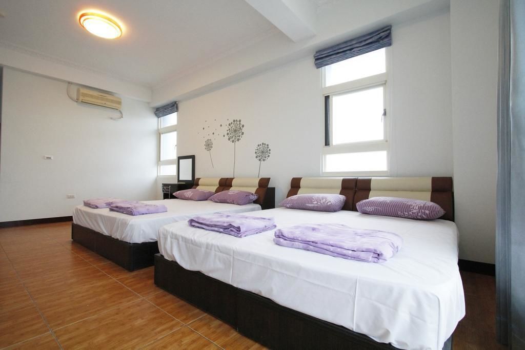 A hotel room with two beds, a ceiling fan, and a window with curtains.