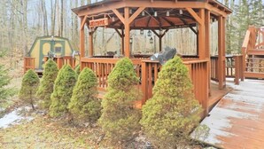 Un kiosque en bois avec une pancarte indiquant « BIENVENUE », entouré de petits arbres et doté d’une terrasse en bois.