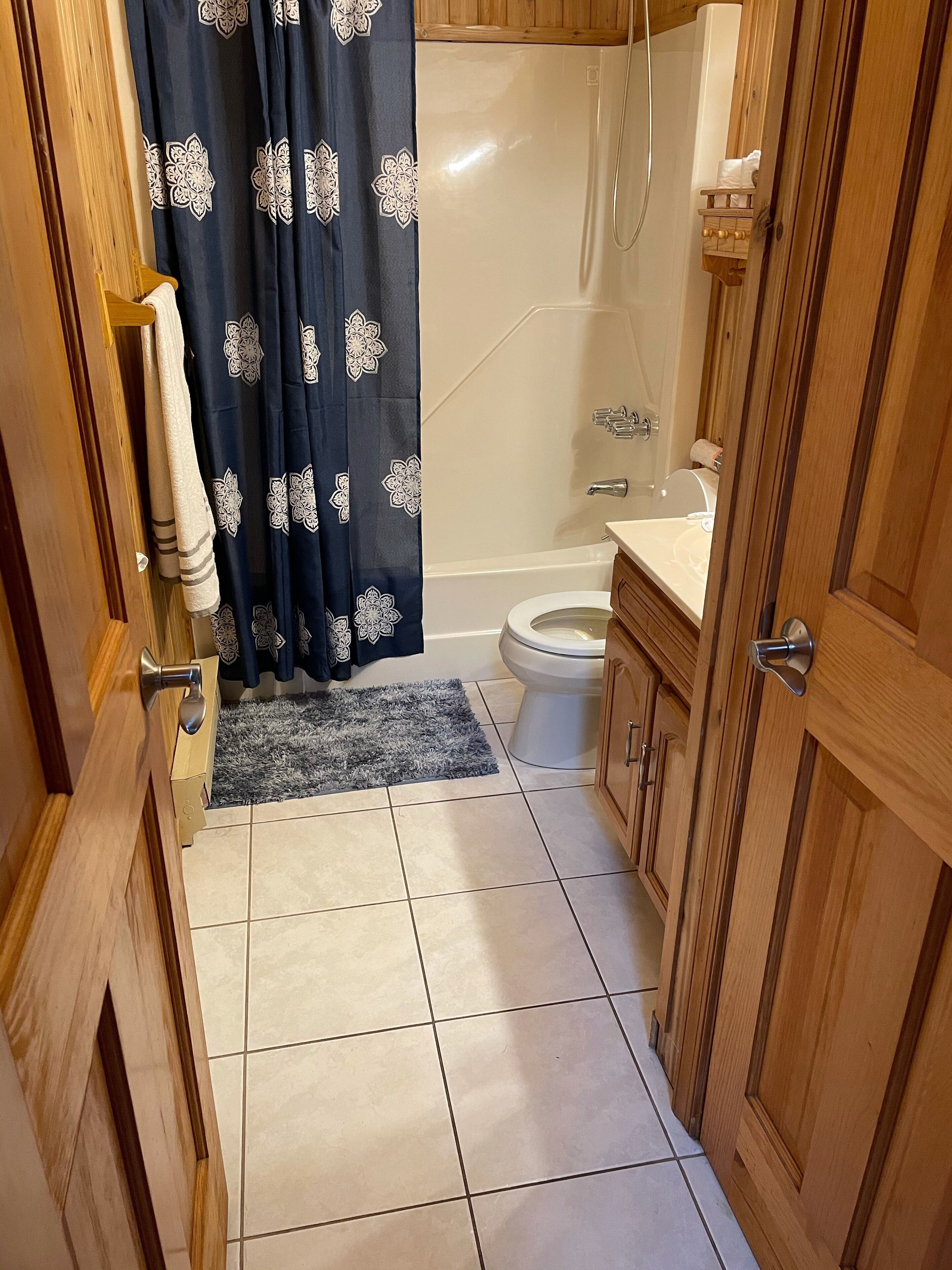 Ein Badezimmer mit Toilette, Badewanne, Dusche und Holzschränken.