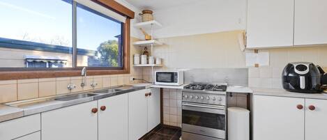 Een oven, een kookplaat, kookgerei, borden en bestek