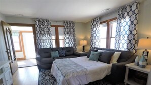 Une chambre à coucher avec un grand lit, un canapé, des rideaux à motifs et un tapis à motifs.