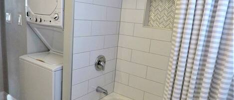 A bathroom with a shower, a toilet, and a washing machine.