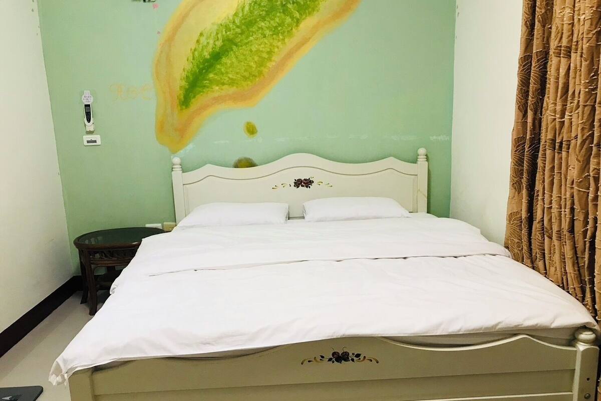 A bed with white bedding in a room with green walls.