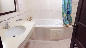 Un baño con un lavamanos, dos grifos, una bañera y una cortina de ducha.