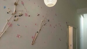 Un pasillo con pared blanca, una lámpara colgante y una puerta al final.