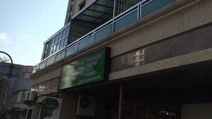 Un edificio de varios pisos con balcones y un letrero verde.