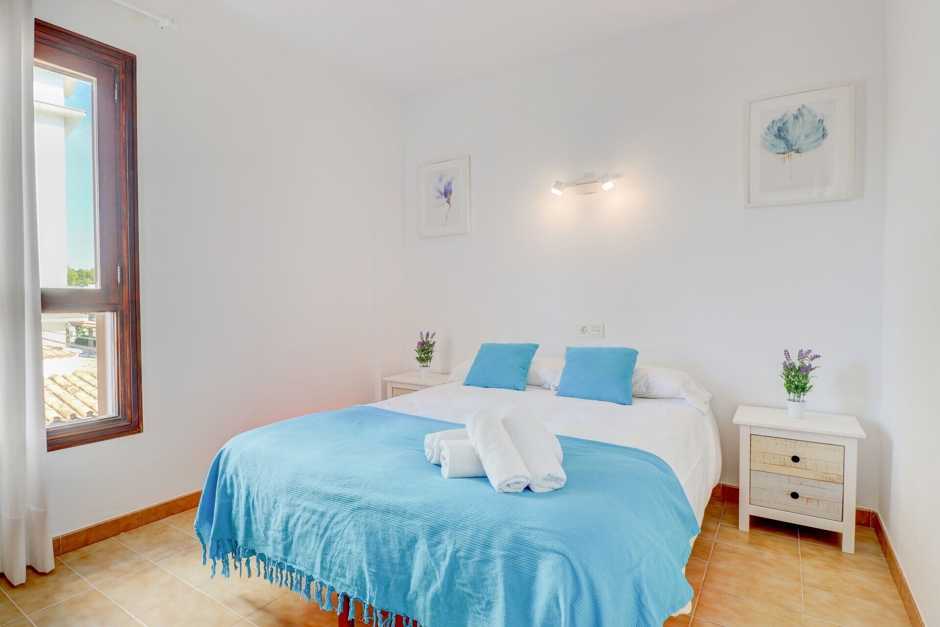 A bedroom with a bed, two bedside tables, and a window.