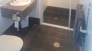 A bathroom with a sink, mirror, toilet, and a glass-enclosed shower. - Jopen Cafe & Motel (Sussex Inlet)