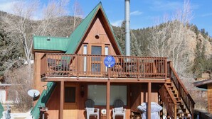 Una cabaña de madera con balcón, chimenea y un cartel que indica que es un alquiler vacacional.