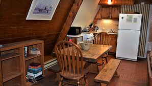 Una cocina acogedora con muebles de madera, una mesa de comedor y un refrigerador.