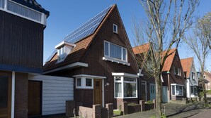 A residential house with a sloped roof, solar panels, and a garage.