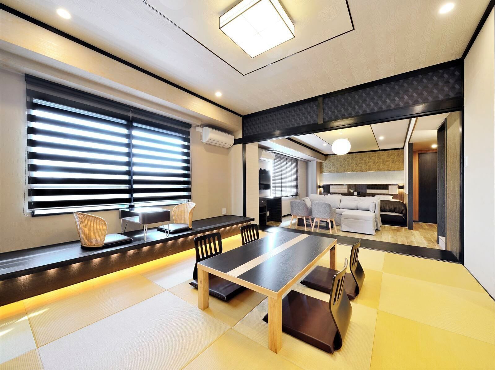 A modern living room with a dining area, large windows with blinds, a sofa, and a television.