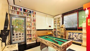 Une table de billard dans une pièce dotée d’étagères à livres et d’un présentoir de cartes.