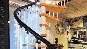 Un escalier en colimaçon avec des marches en bois et un tuyau noir flexible qui longe son pourtour.