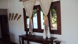 A room with a wooden table, two white vases, a small statue, and a patterned rug.