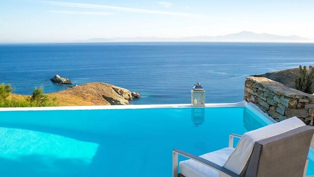 A infinity pool with a clear view of the sea and mountains.
