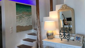 A staircase with a beach painting, a lamp, and a mirror with a guitar.