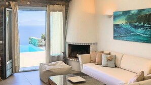 A modern living room with a stone wall, a fireplace, a sofa, a coffee table, and a painting of the ocean.