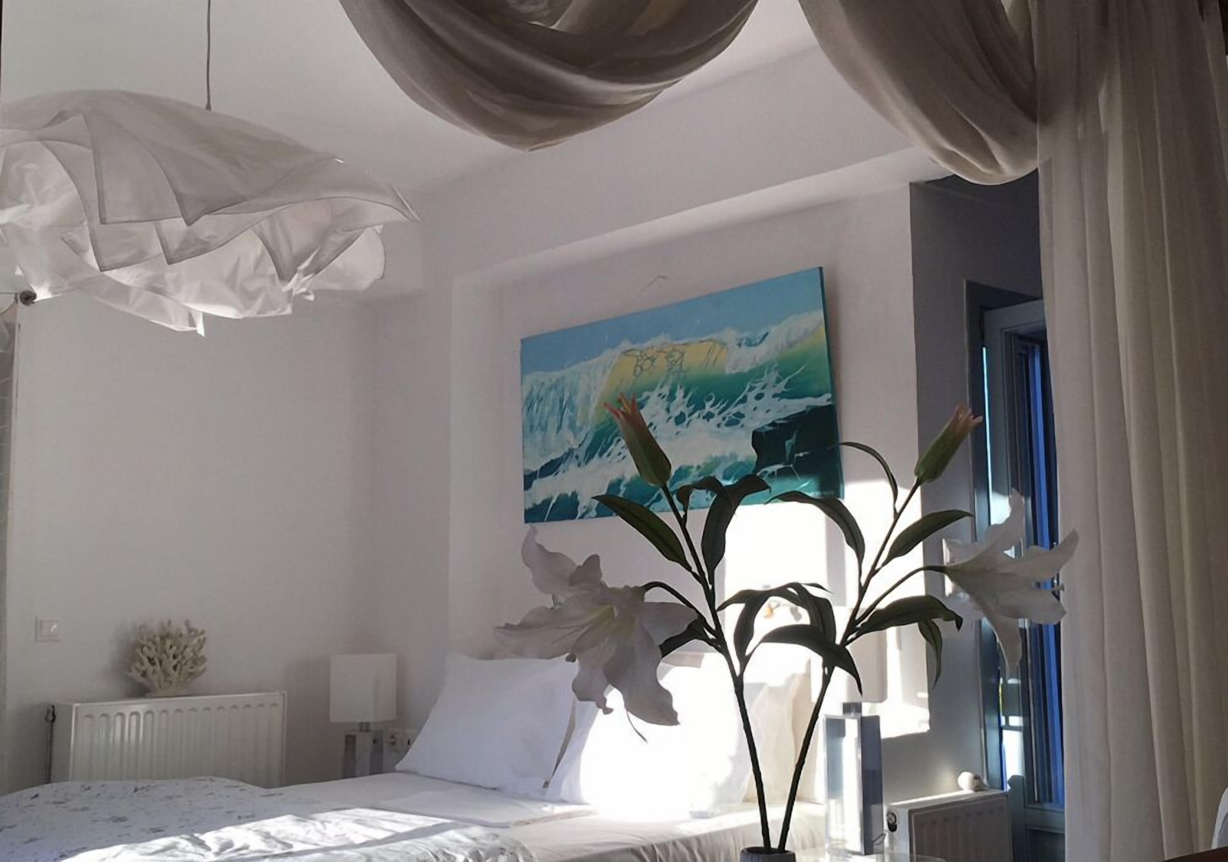 A bedroom with a bed, a radiator, a lamp, a painting of a wave, and a plant.