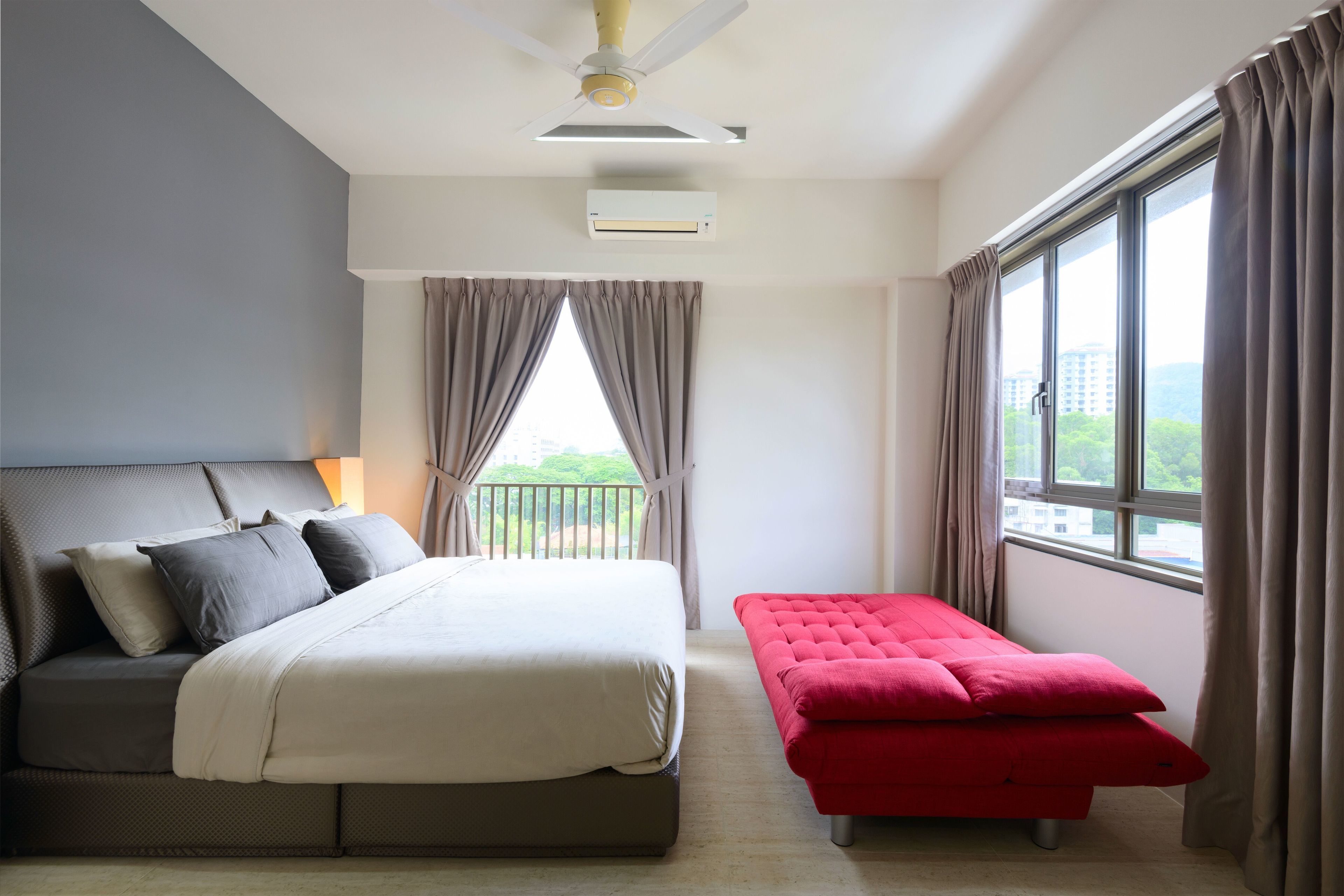 A bedroom with a bed, a bench, a ceiling fan, and a window with curtains.