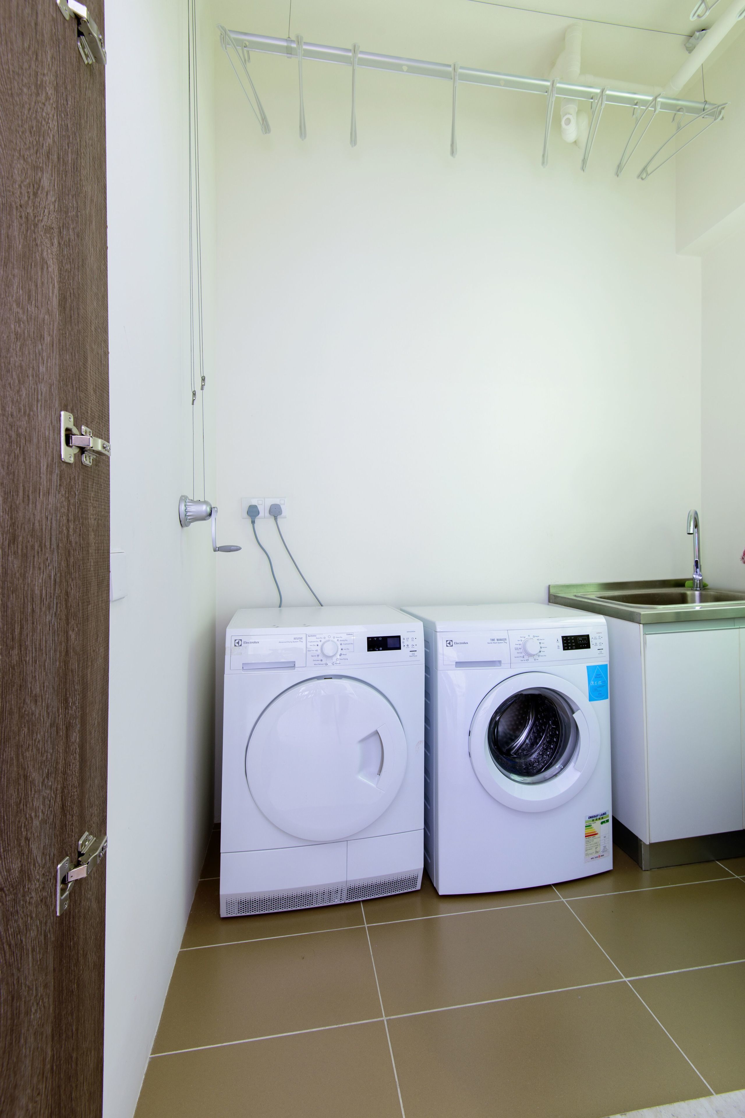 A laundry area with two washing machines, a metal drying rack, and a sink.