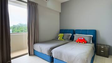 A bedroom with two beds, a window with curtains, a nightstand, and a view of greenery outside.